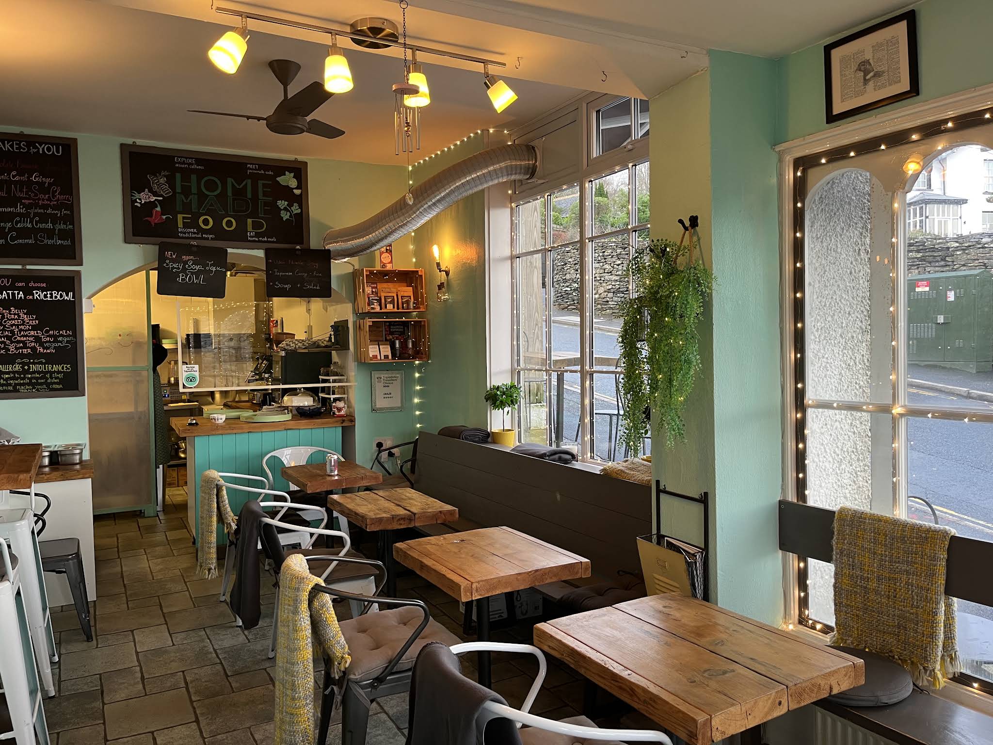 Graze Cafe's green interior with wooden tables, window seats, plants and the counter